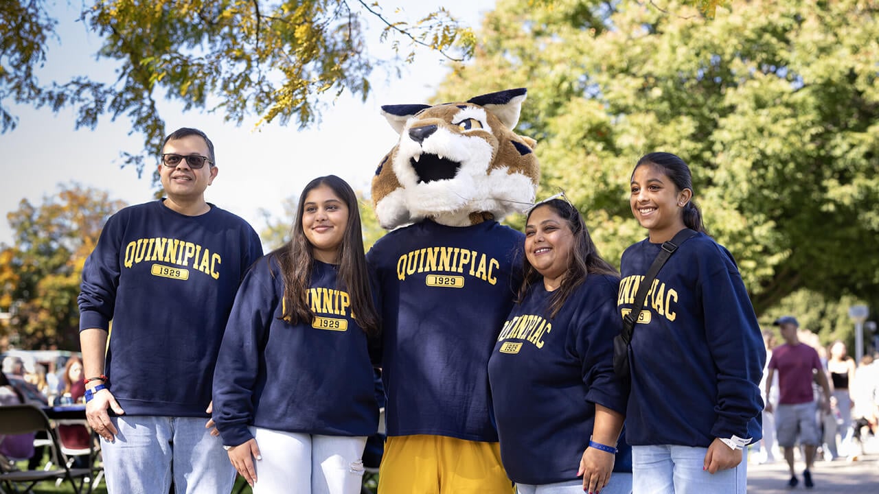 Family wearing matching Quinnipiac shirts with Boomer.