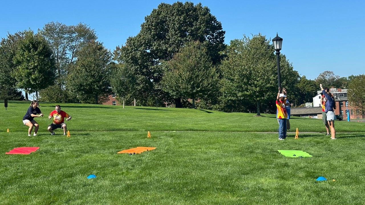 Two groups of athletes stand on opposite side of a field working out.