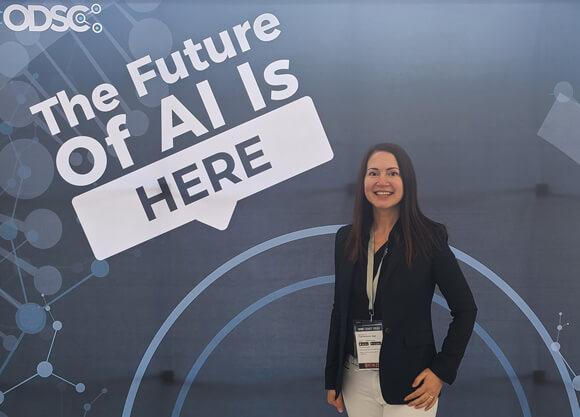 Tamilla Triantoro in front of a backdrop that says "The Future of AI is Here"