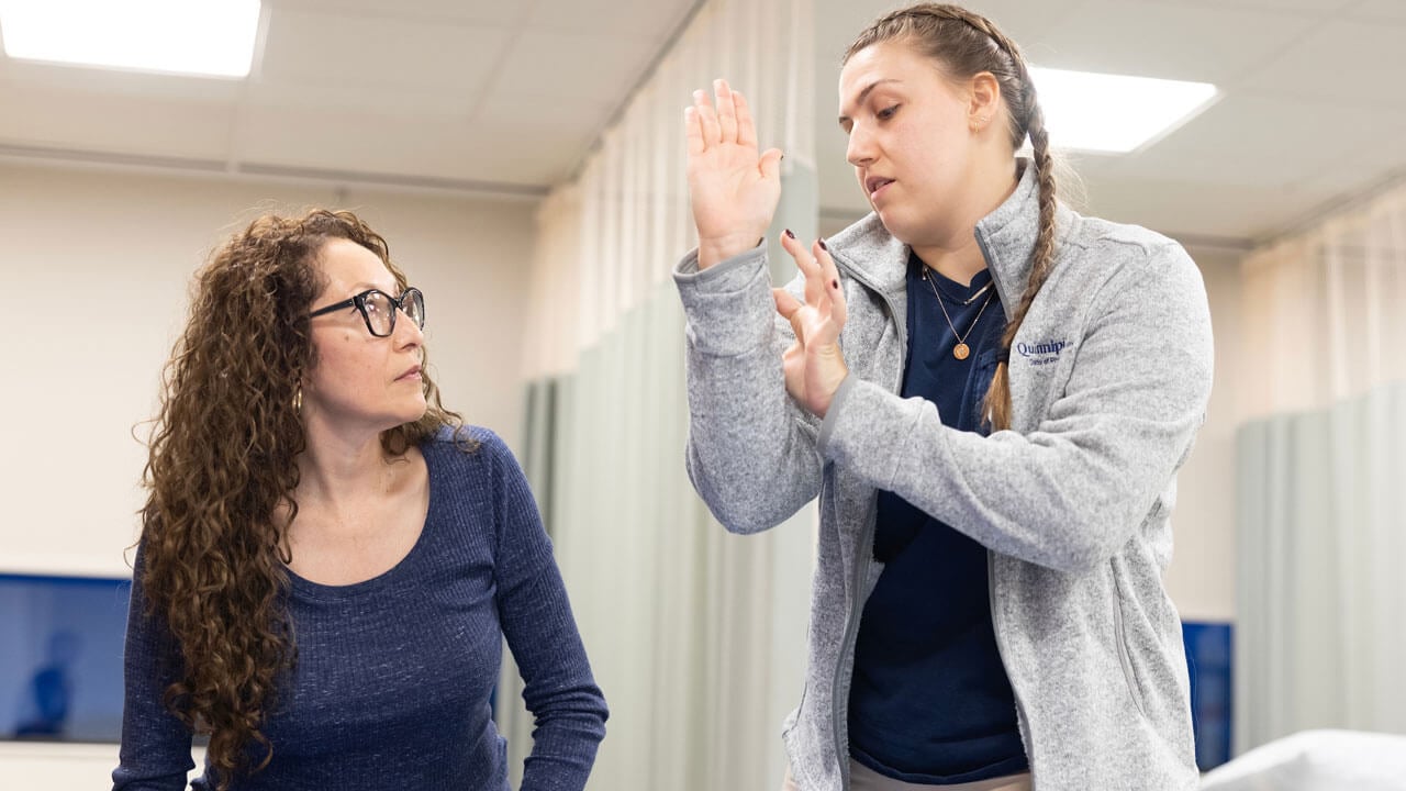An EQUIP Volunteer shows a patient an arm movement