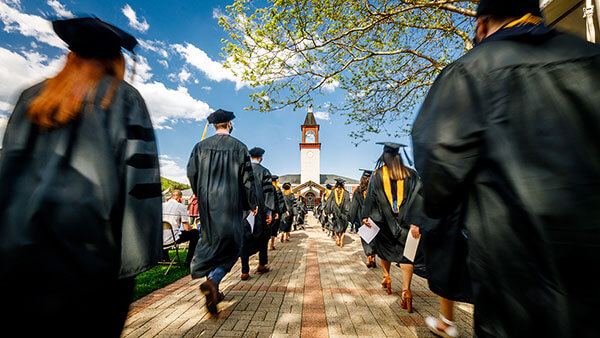 Graduates walk into commencement on the Mount Carmel Quad.