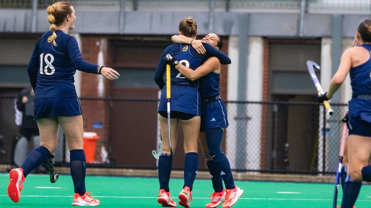 Field hockey players hug.