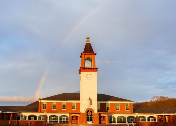 A rainbow in the sky over the Arnold Bernhard Library at dusk