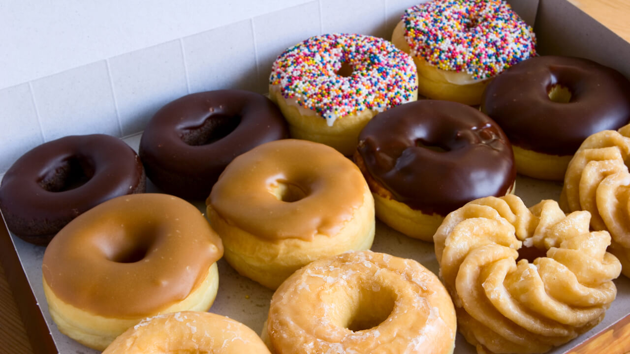 A box of donuts, chocolate glazed, maple, sprinkles, honey cruller, traditional
