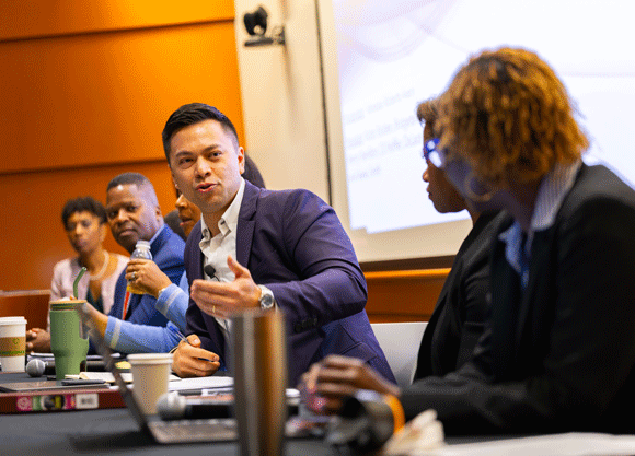 Panelist talking with his hands while looking to the other panelists