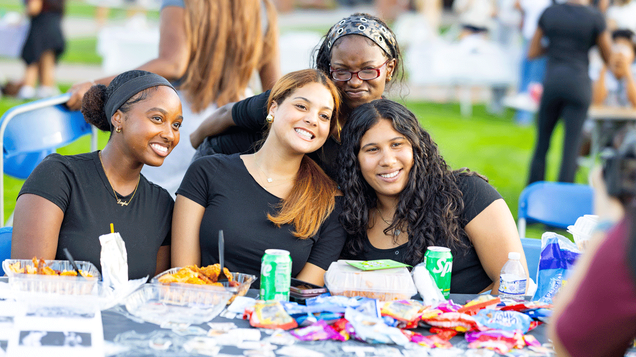 A group of students smile and pose for a photo at the MSLC Culture Fair