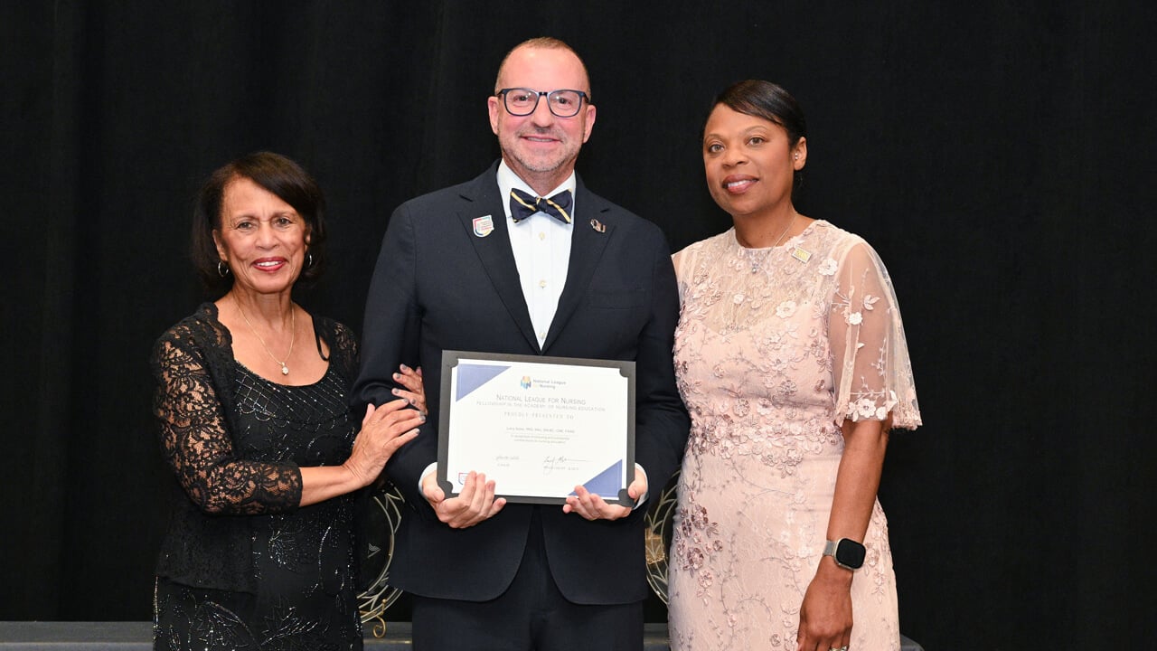 Larry Slater and two women posing for a photo with a framed certificate