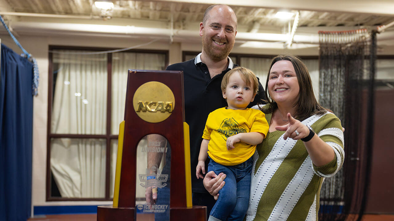 Family smiles in front of the NCAA National Championship trophy