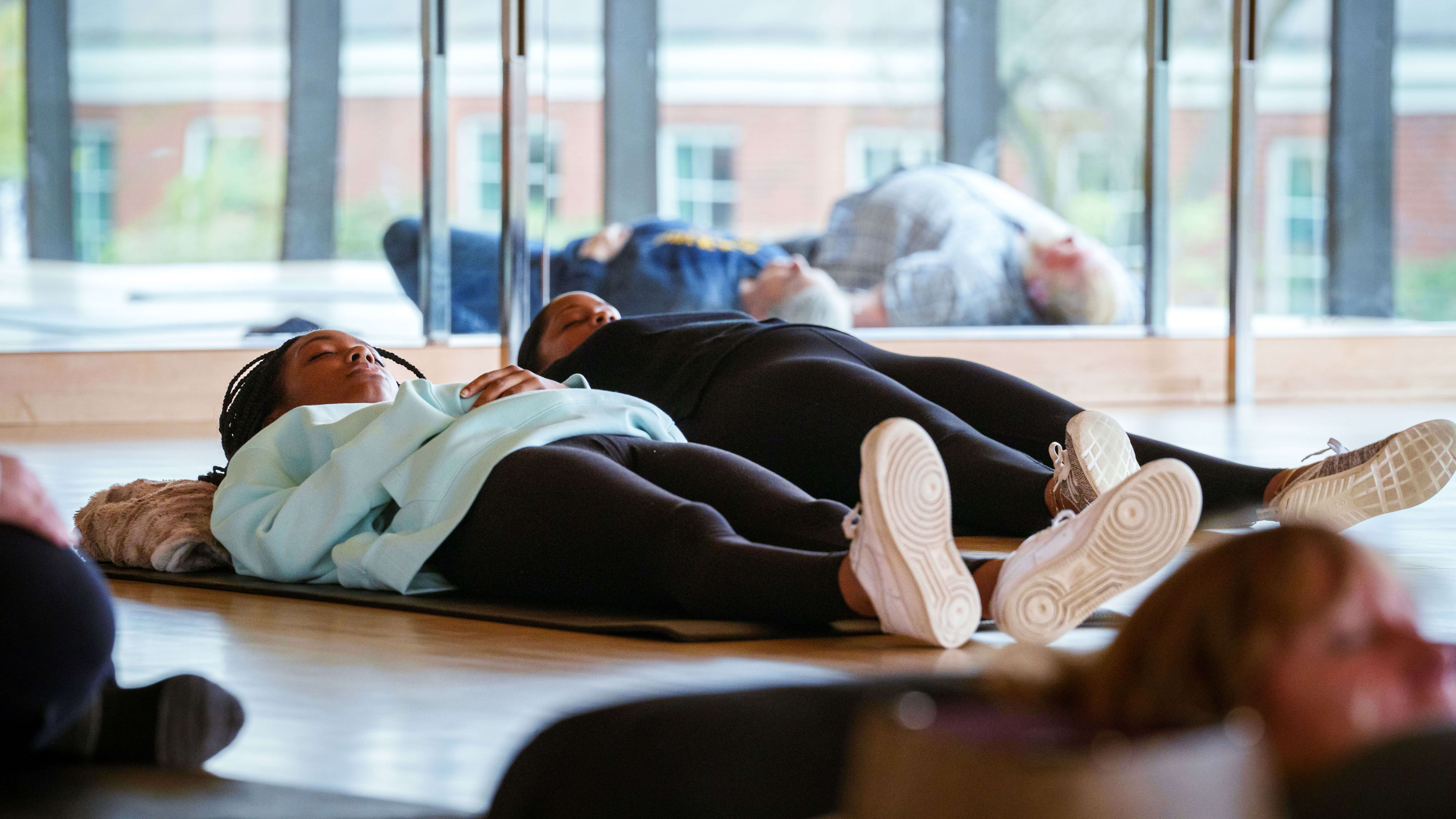 Two women lay down on yoga mats during a mindfulness event on bobcat weekend.
