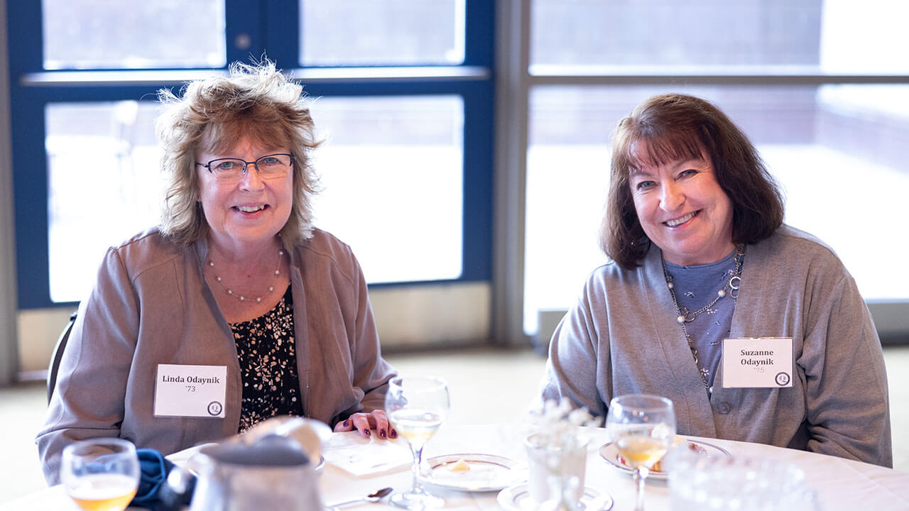 Two alumnae smile while sitting down at the Alumni Heritage Luncheon