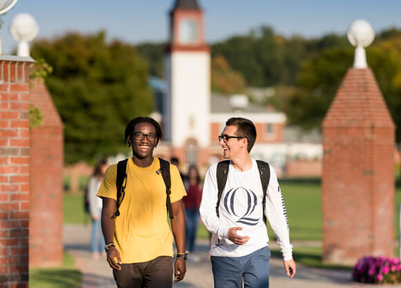 Two students walking in front of the Arnold Bernard Library on the Mount Carmel Campus.
