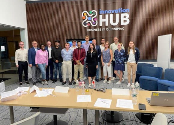 Quinnipiac and polish business students pose in front of the innovation hub sign during the pitch competition.