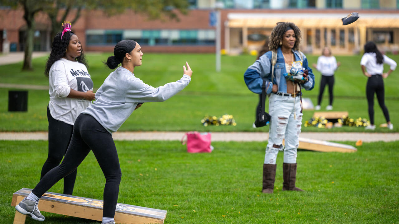 Students toss bean bags while playing cornhole