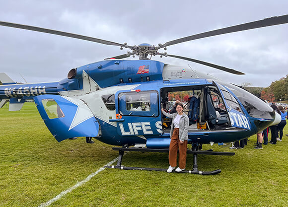 Ephe Nicolakis stands in front of the LIFE STAR helicopter.