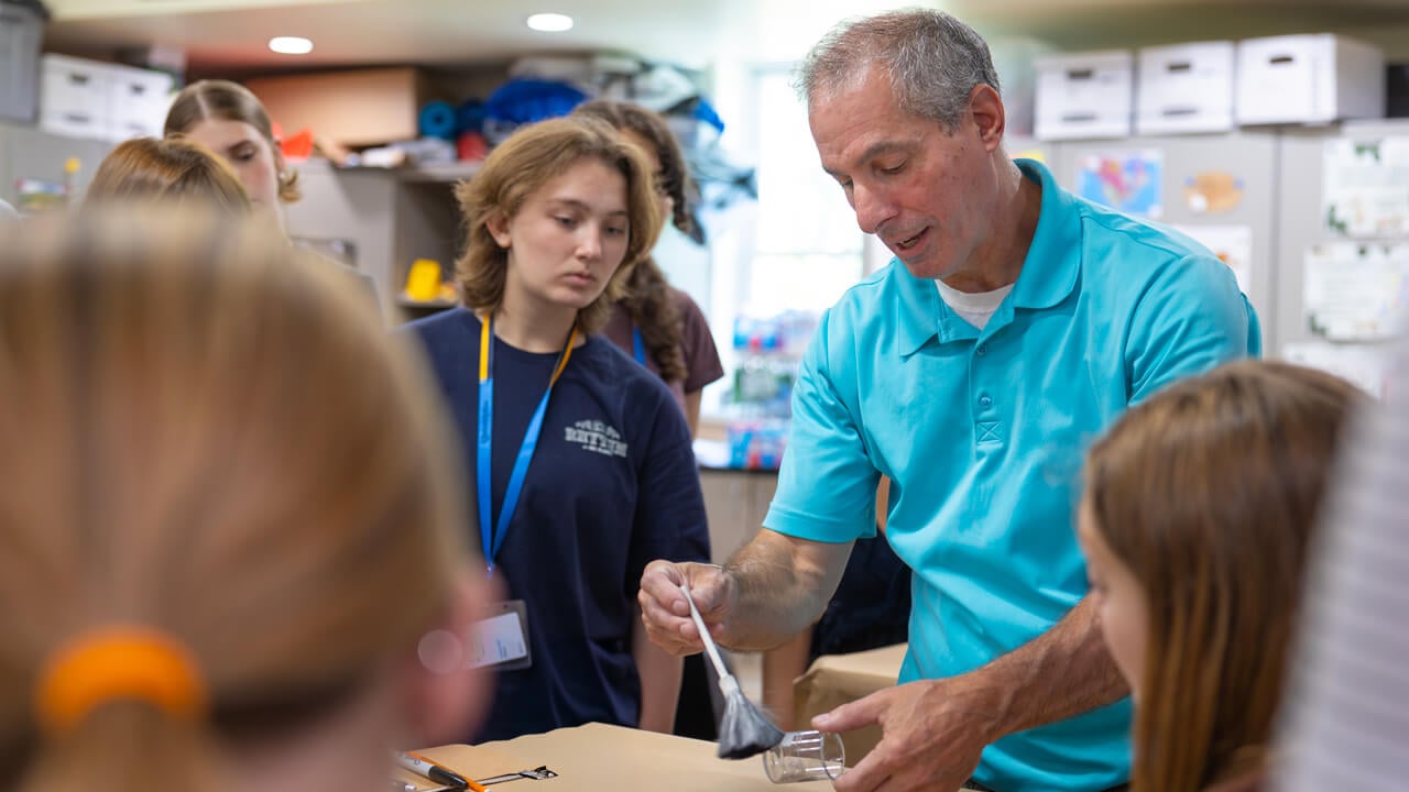 An instructor demonstrates fingerprint dusting techniques to a group of high school students in a forensic science classroom at Quinnipiac University.