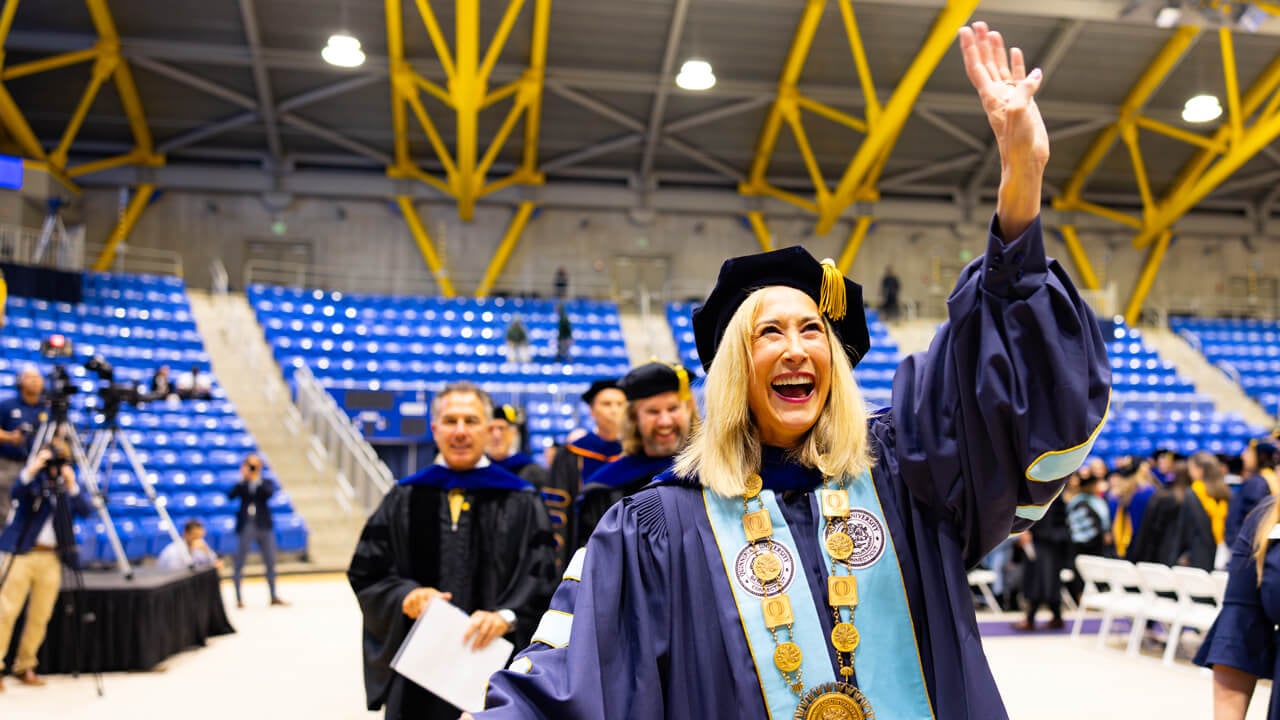 Marie Hardin waving to the crowd as she walks into the ceremony