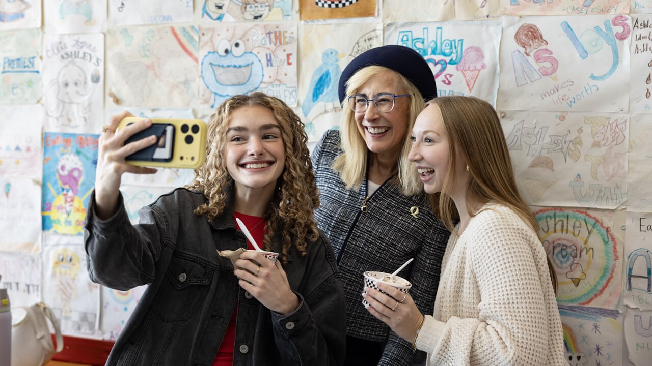 Marie Hardin and two students hold ice cream cups and pose for a selfie
