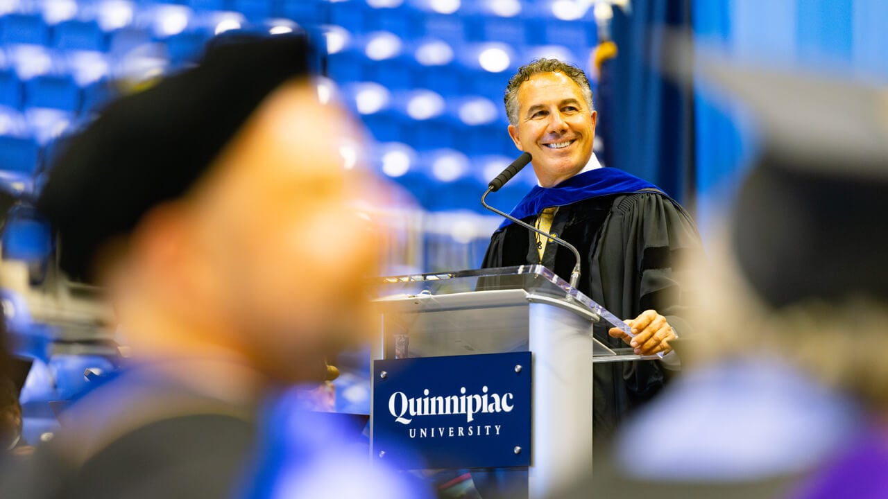 Chuck Saia smiles at the podium on stage