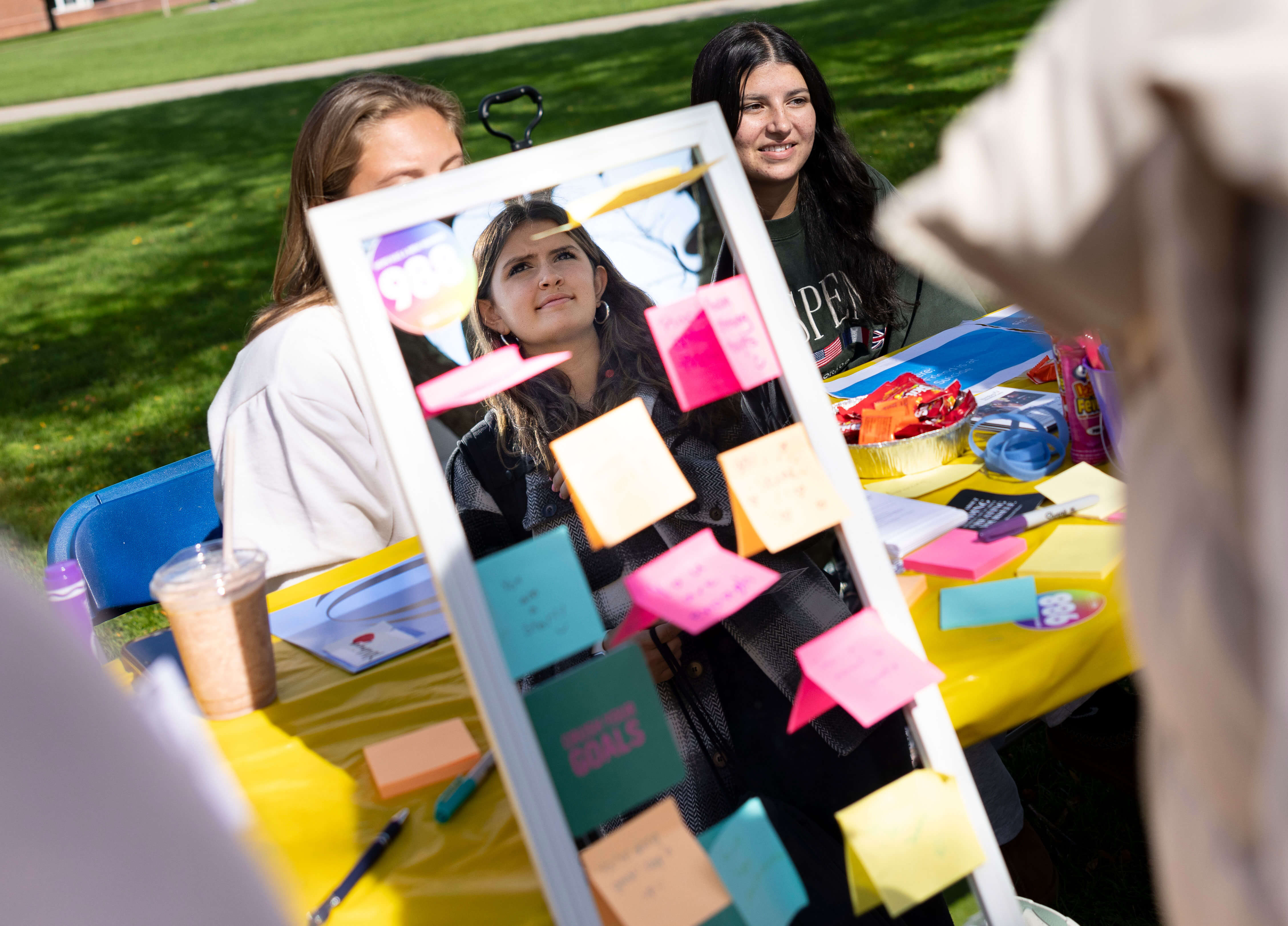 A student looks into a mirror with post-it notes plastered onto it.