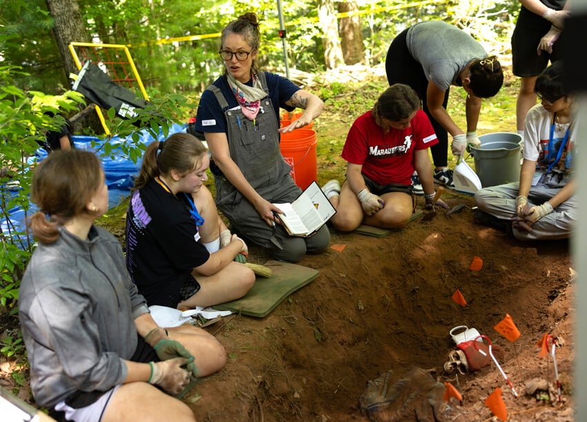 A professor gives direction to high school students participating in a hands-on forensic science lab.
