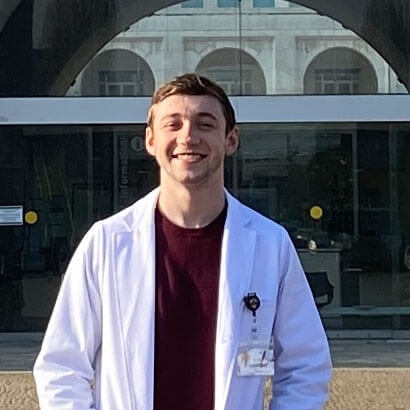 Evan Gundling in a lab coat outside a medical facility