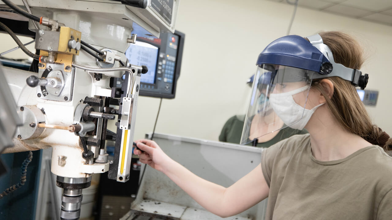 A female student operating on a manufacturing machine