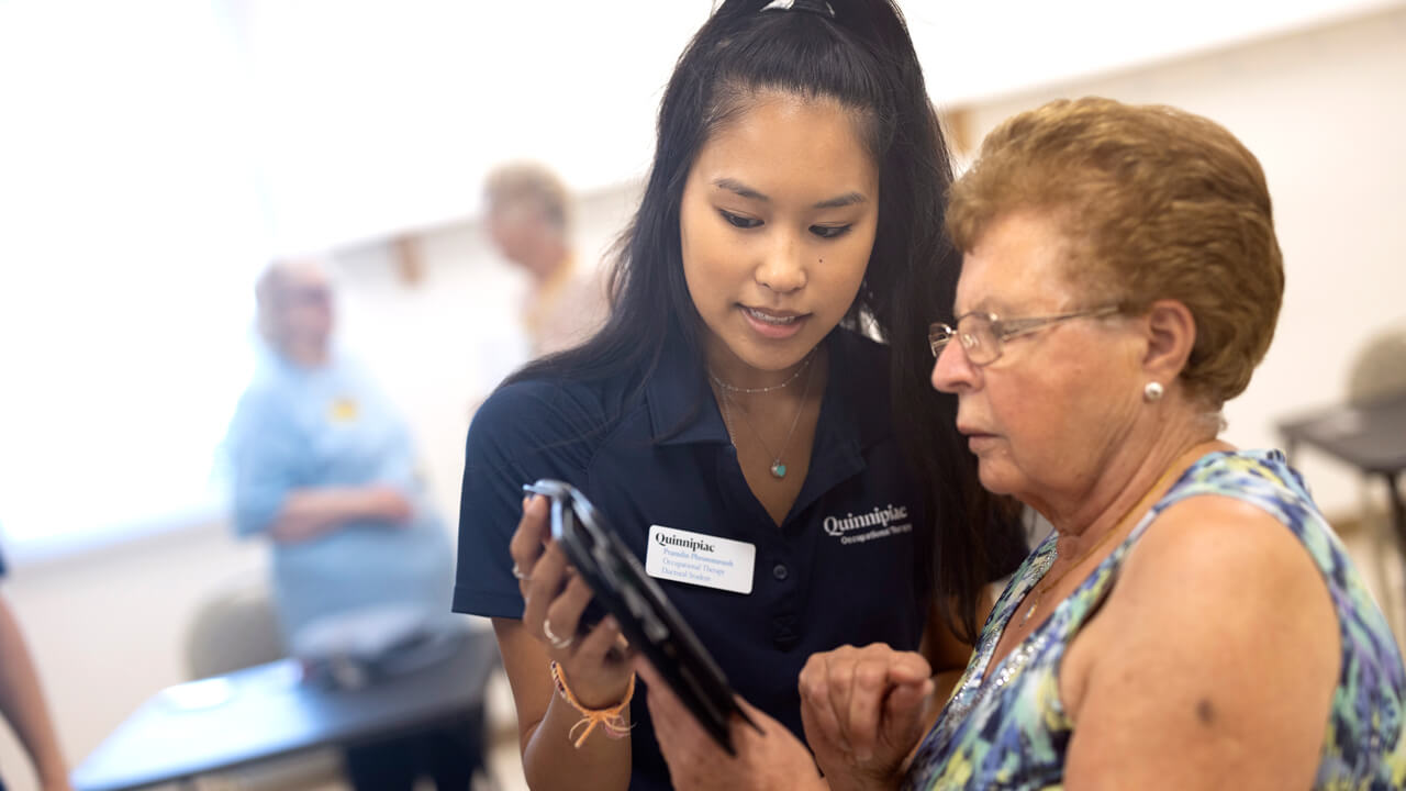 An occupational therapy student works with an older adult on her mobile device