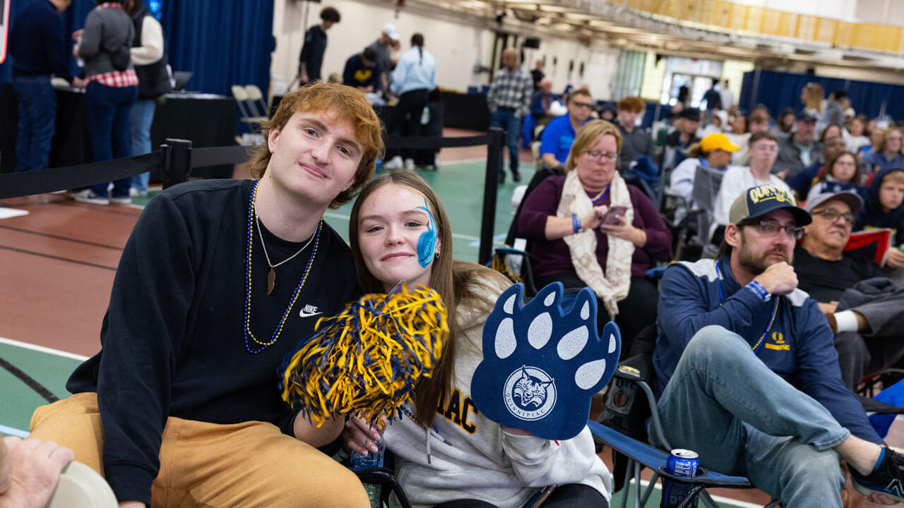 Two students holding up some Quinnipiac gear