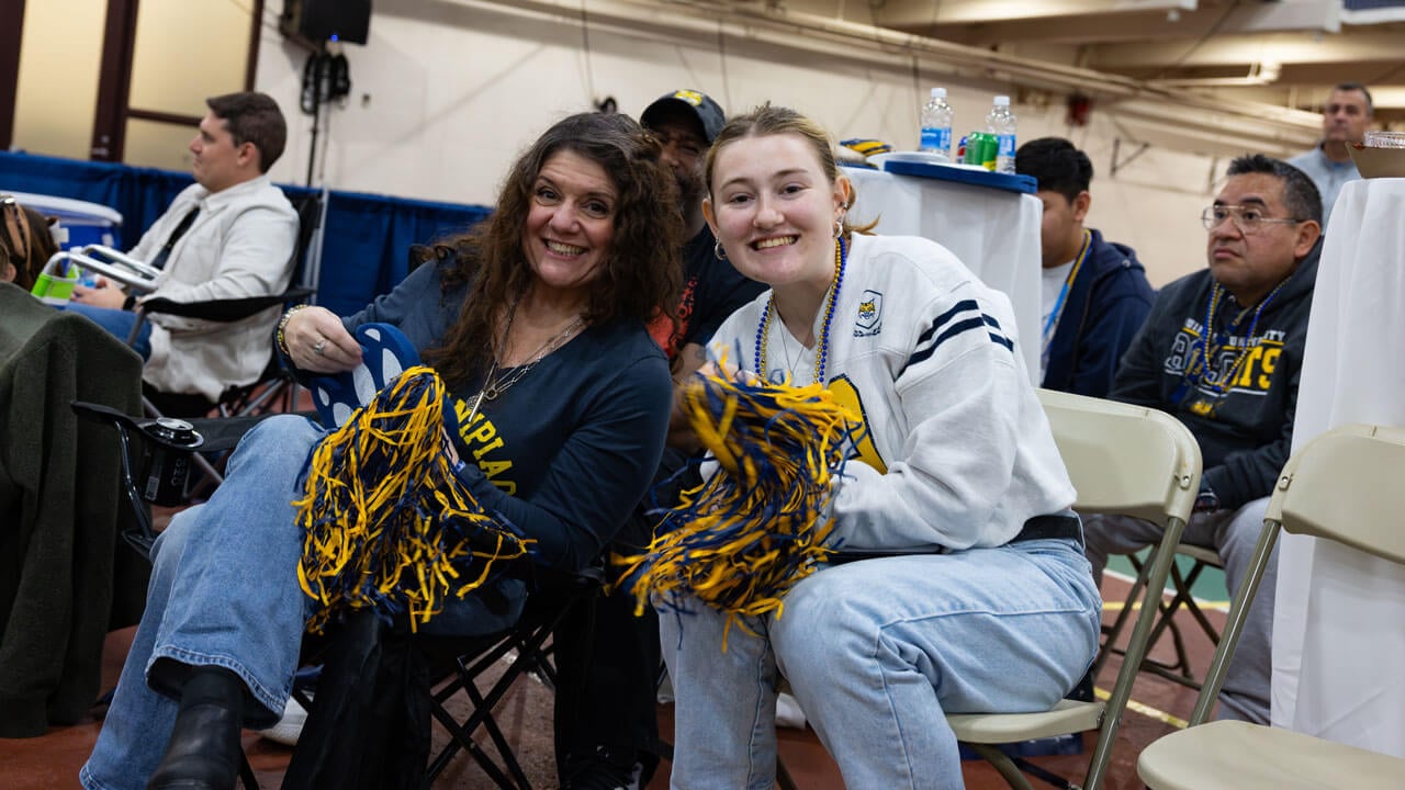 Two individuals smiling while holding bobcat gear