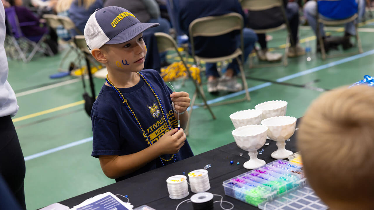 Child participates in some arts and crafts while decked out in Quinnipiac gear