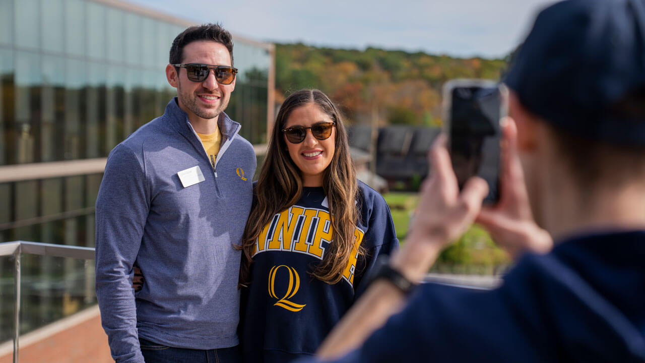 A couple smiles and poses side by side together for a photo