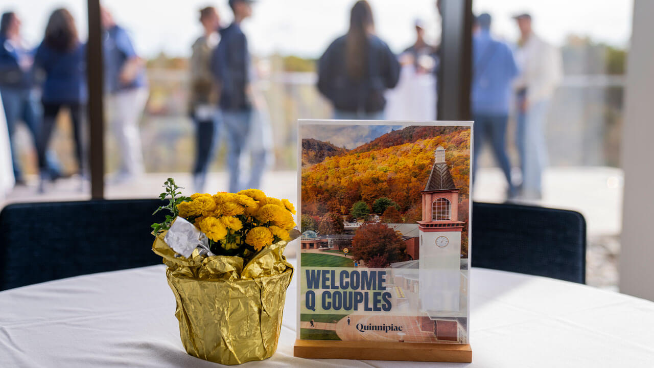 Table setting that reads "Welcome Q Couples" with some flowers next to it