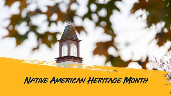 Native American Heritage Month. Clocktower of the Arnold Bernhard Library seen through leaves on a tree.