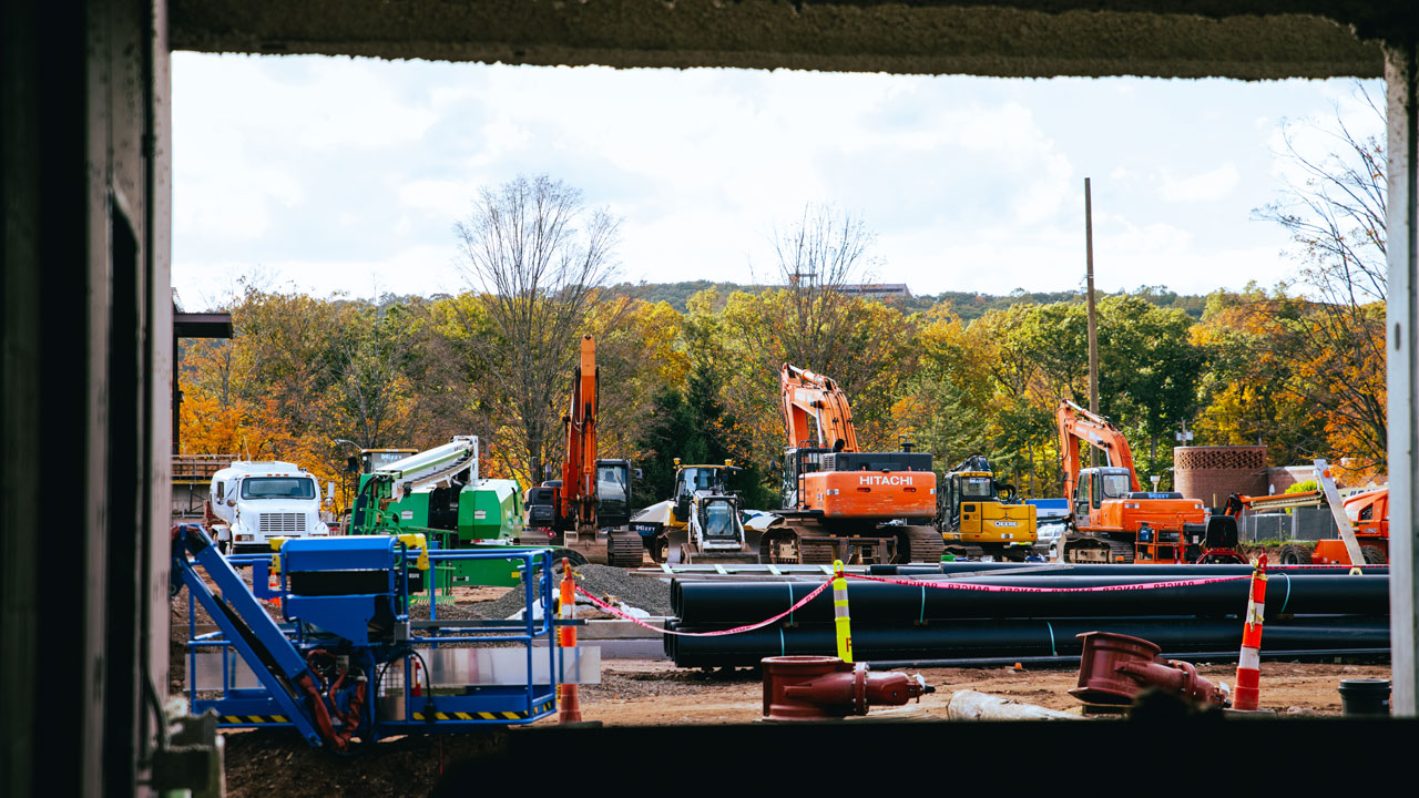 Many construction vehicles against the fall tree landscape of Quinnipiac/