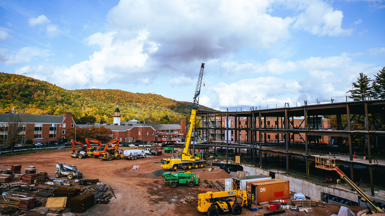 A wide view of the south quad construction with the fall landscape behind it.