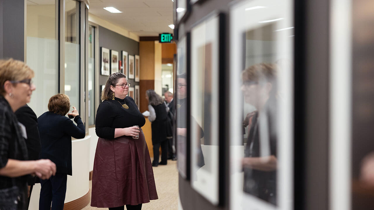 A woman takes in the new gallery on the walls of the School of Law