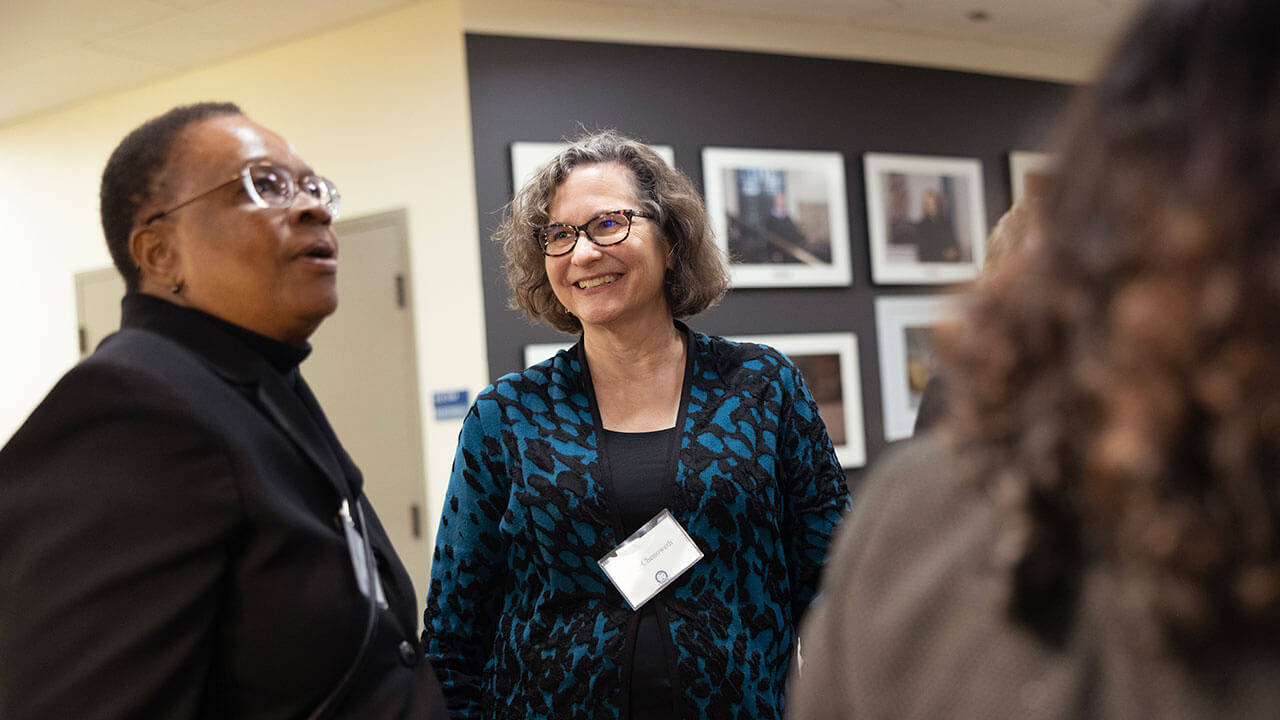 A woman smiles and laughs during a School of Law gallery exhibit