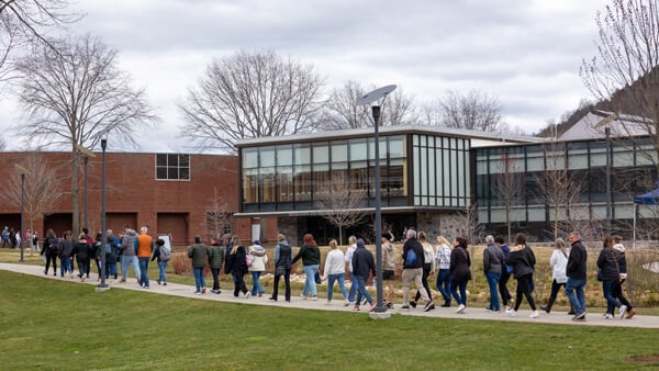 A large group tour walks in front of the Quinnipiac Recreation and Wellness Center