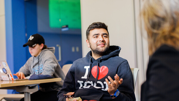 An international student sits and talks with someone on comfy couches
