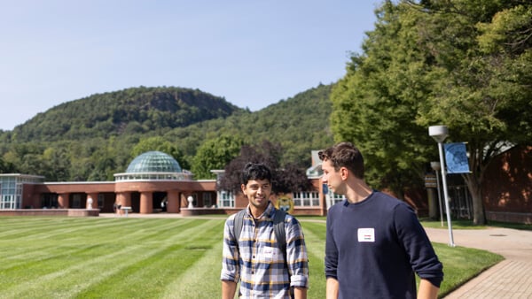 Two international students walk across the quad with the Sleeping Giant mountain in the distance