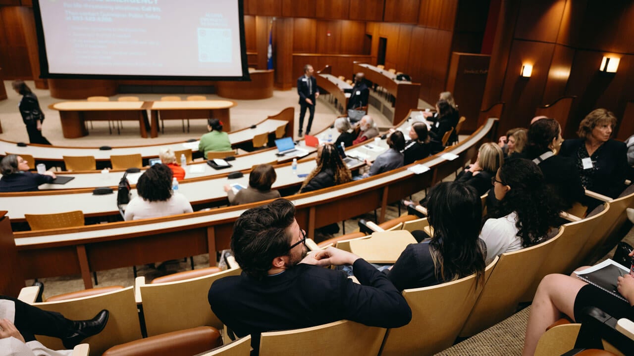 View of a wooden auditorium with individuals sitting in the crowd
