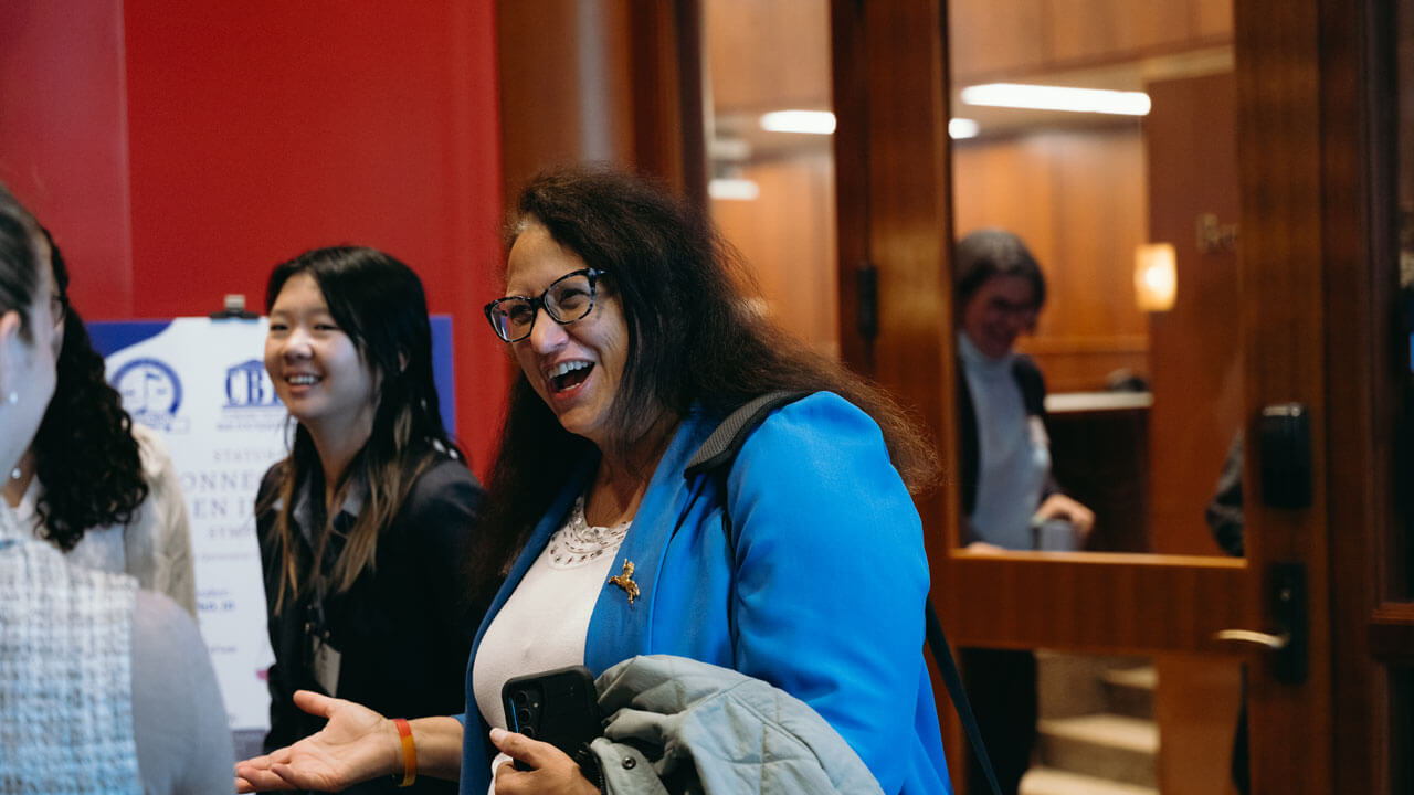 Woman in a blue blouse talks to a colleague while making a hand gesture