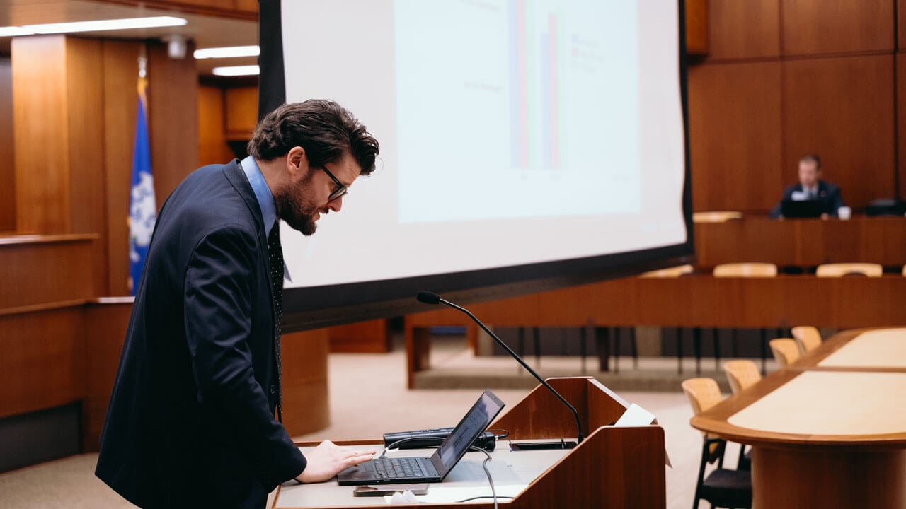 Speaker looking down at his computer while he talks at a podium