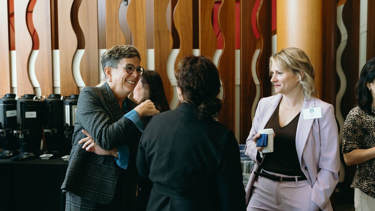 Three individuals talking amongst each other while smiling