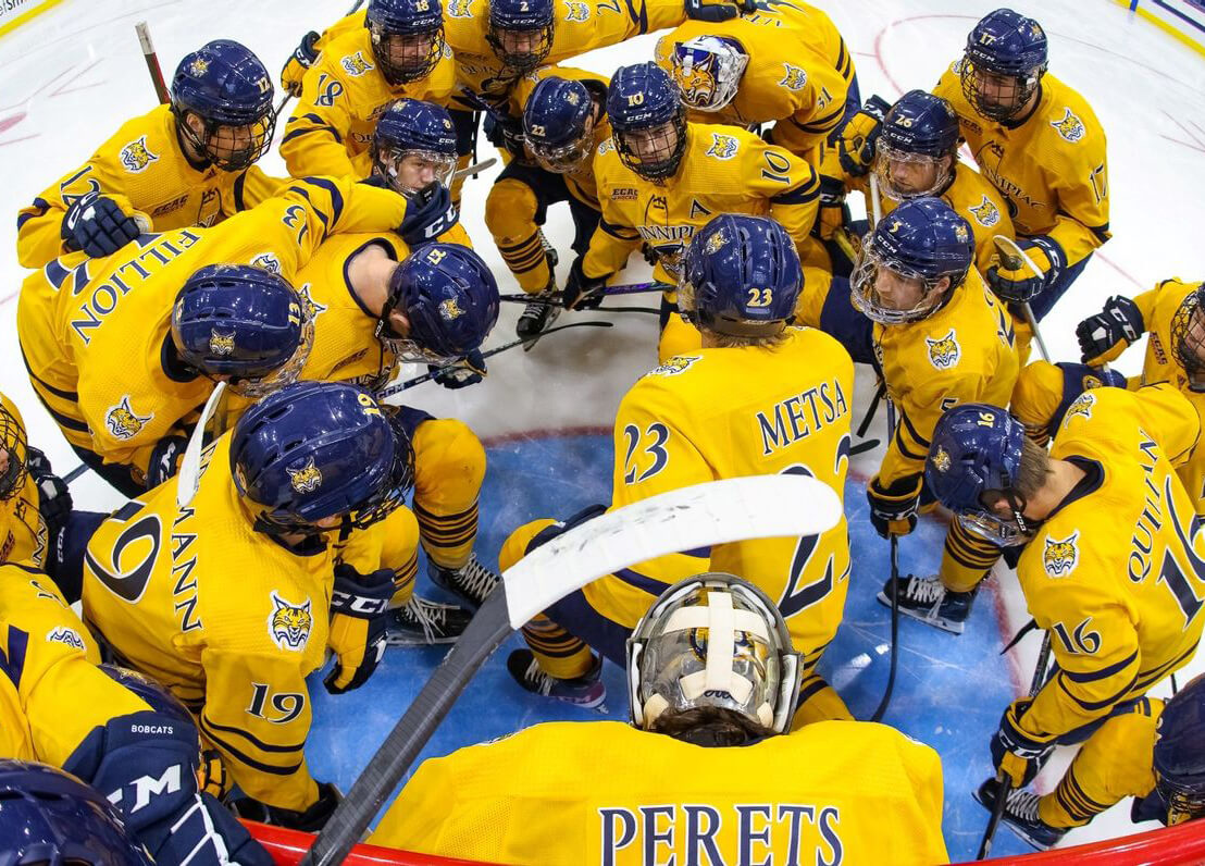 Men's ice hockey team gathers around the goal