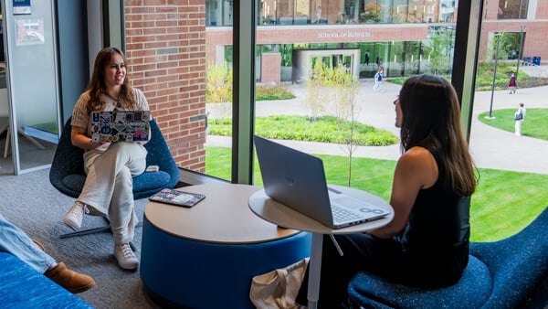 Two students study together at comfy chairs in The SITE
