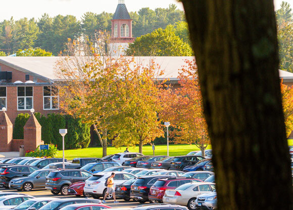 A student walks by parked cars on the Mount Carmel Campus.