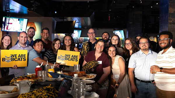 Quinnipiac Alumni holding up signs and enjoying an event at a bar.