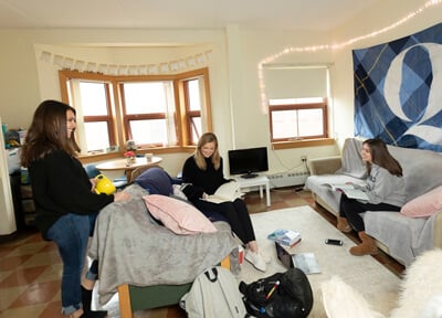 Four roommates talk in their apartment common room and kitchen in Westview