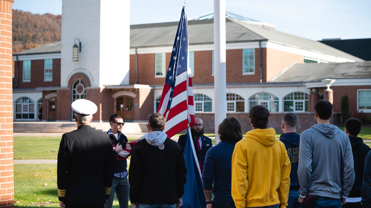 Members of the military raise a flag on Quinnipiac's quad